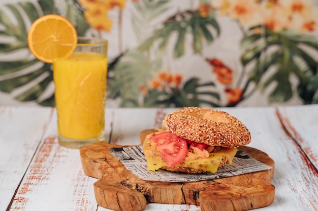 Delicious bagel with sesame and chia bread, inside it contains tomato, ham and chicken in strips.