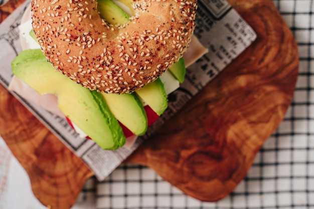 Delicious bagel with sesame and chia bread, inside it contains tomato, ham, fresh cheese and some freshly extracted slices of avocado.
