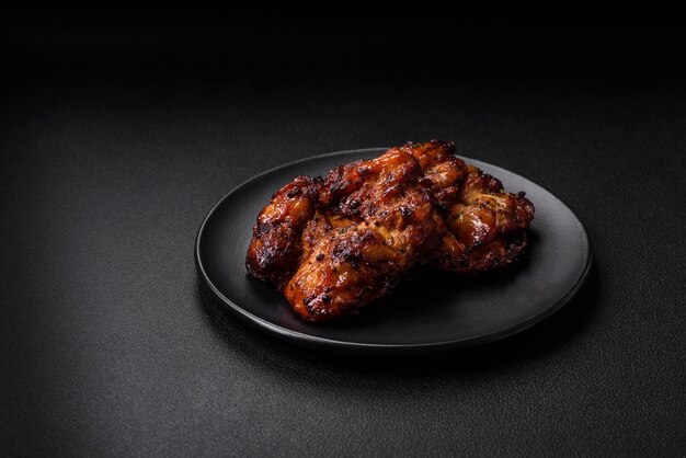 Delicious baked chicken meat with salt spices and herbs on a dark concrete background