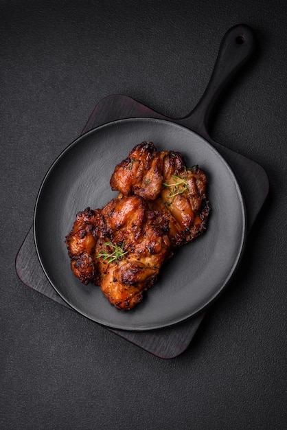 Delicious baked chicken meat with salt spices and herbs on a dark concrete background