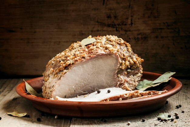 Delicious baked ham pork on a clay tray on the old wooden background selective focus