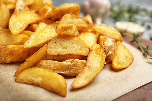 Delicious baked potato wedges on parchment paper closeup