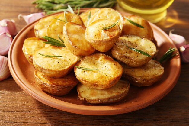 Delicious baked potato with rosemary in bowl on table close up