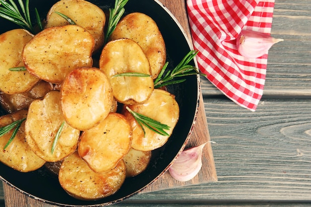 Вкусный запеченный картофель с розмарином в сковороде на столе крупным планом