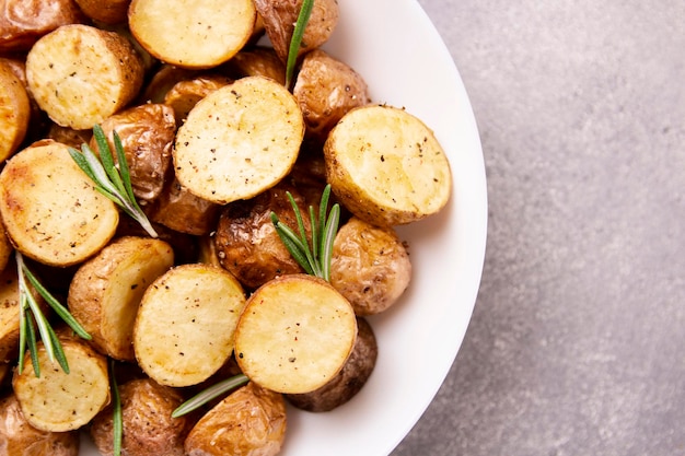 Вкусные запеченные картофели с розмарином на сером фоне