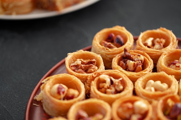 Delicious baklava dessert in oriental setting on black background