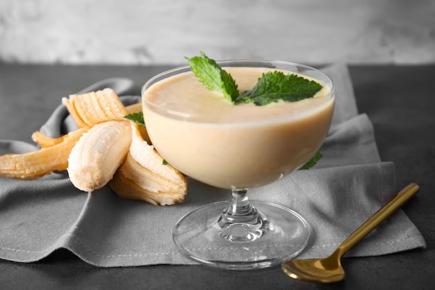 Delicious banana homemade smoothie in dessert bowl on grey background