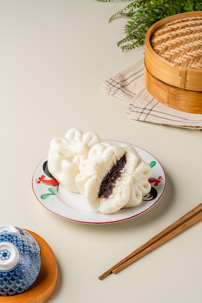 Вкусная китайская мясная булочка Baozi на пару готова к употреблению на сервировочной тарелке и пароварке.