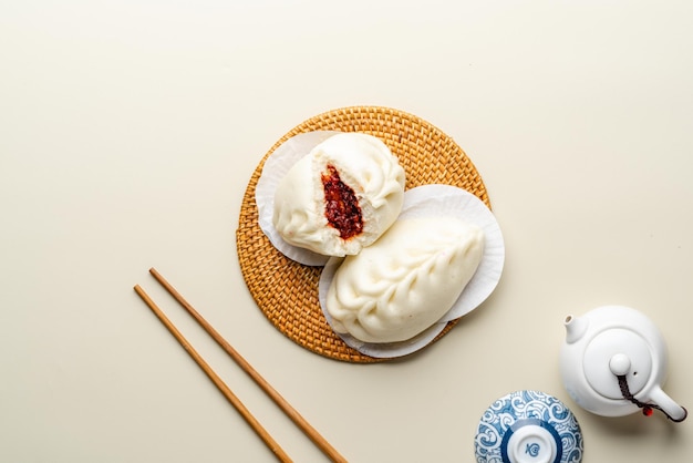 Вкусная китайская мясная булочка Baozi на пару готова к употреблению на сервировочной тарелке и пароварке.