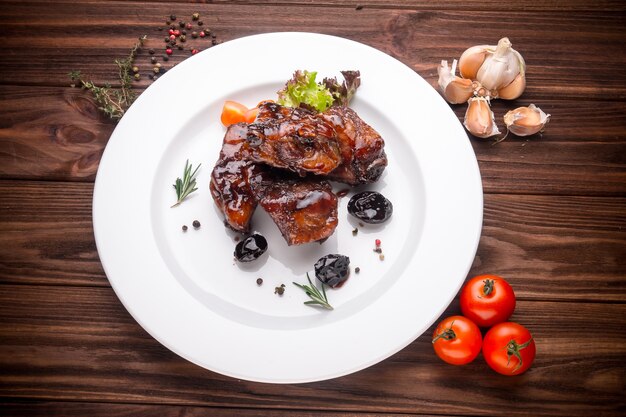 Delicious barbecued ribs seasoned with a spices and fresh herbs on wooden background