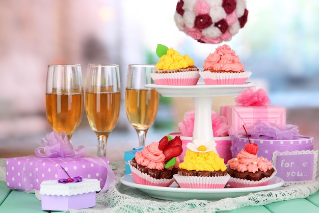 Delicious beautiful cupcakes on festive table on room background