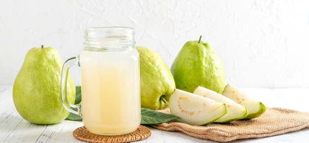 Delicious beautiful guava fruit with fresh juice set isolated on bright white wooden table