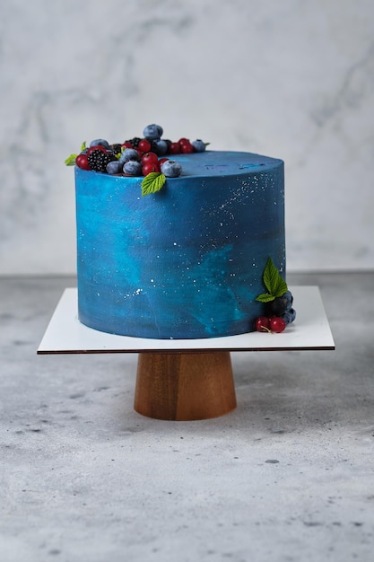 Delicious and beautiful space style cake for a boy or a man. Confectionery for the holiday. Dessert is decorated with fresh blueberries, blackberries, red currants and chocolate.