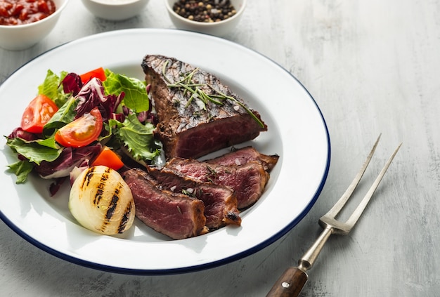 Bistecca di manzo deliziosa con insalata. barbecue di manzo alla griglia affettato con cipolla fritta