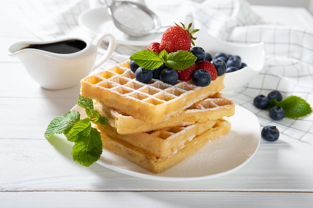 Delicious Belgian waffles with strawberries, blueberries and mint on a plate