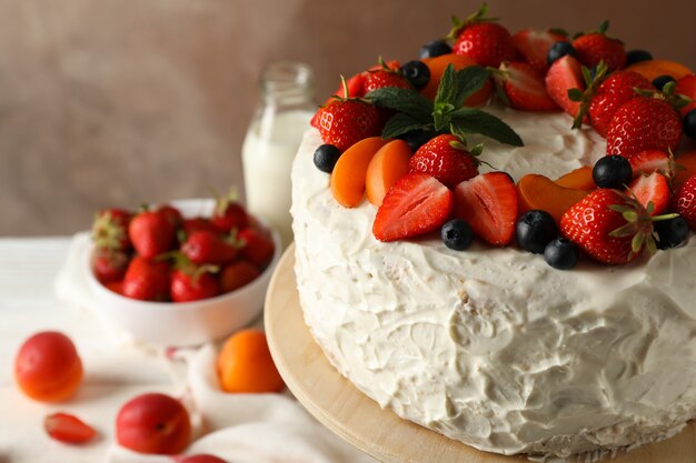 delicious berry cream cake against brown background