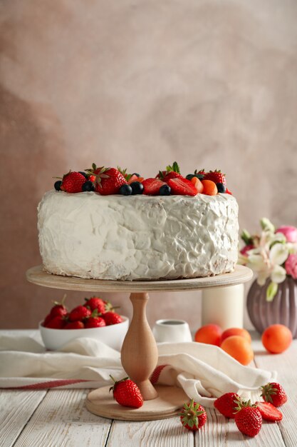 delicious berry cream cake on white wooden table