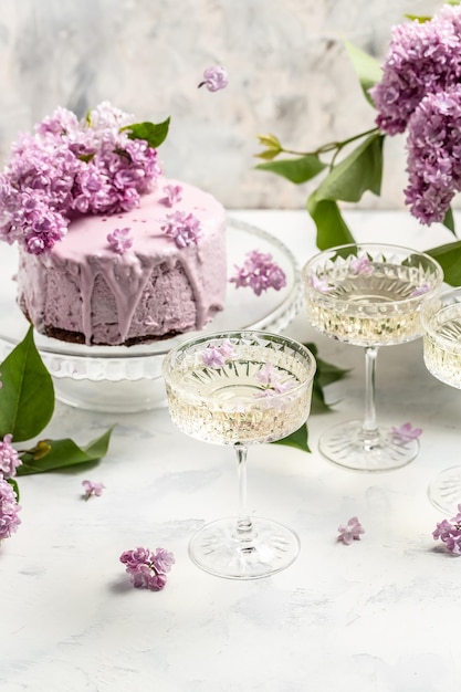 Delicious berry mousse cake with prosecco champagne wine bouquet of purple blooming lilacs French cuisine postcard background