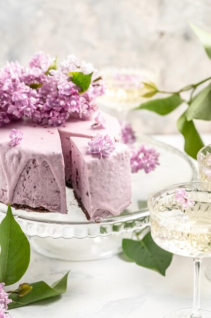 Delicious berry mousse cake with prosecco champagne wine bouquet of purple blooming lilacs French cuisine postcard background