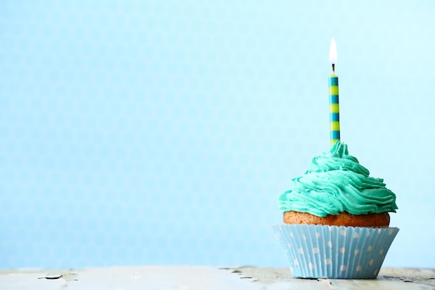 delicious birthday cupcake on blue background