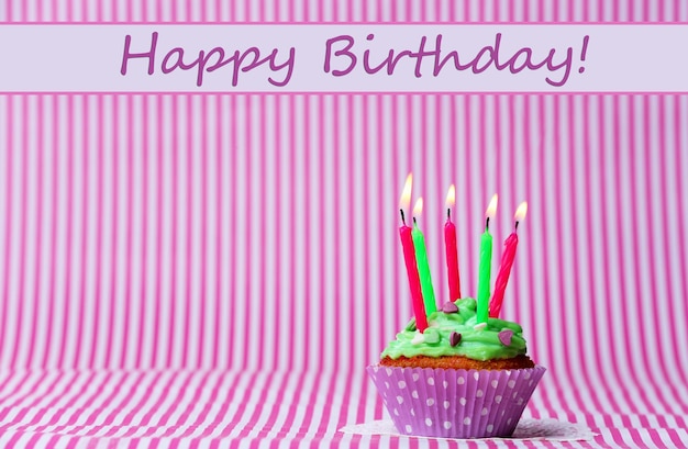 Delicious birthday cupcake on pink background