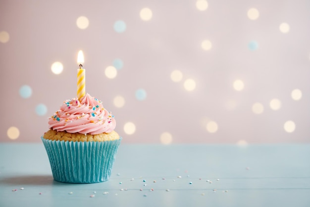 Delicious birthday cupcake on table on light background