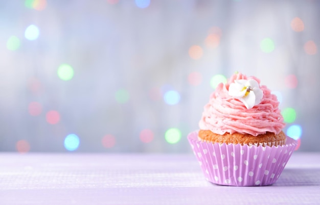 Delicious birthday cupcake on table on light background