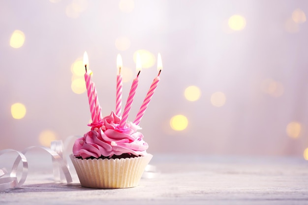 Delicious birthday cupcake on table on light background