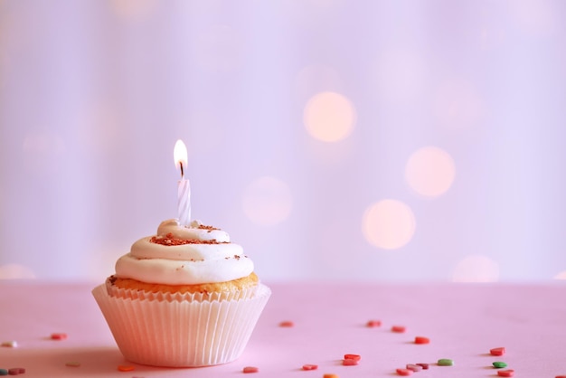 Delicious birthday cupcake on table on light background