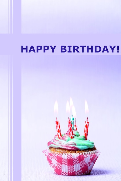 delicious birthday cupcake on table on light background