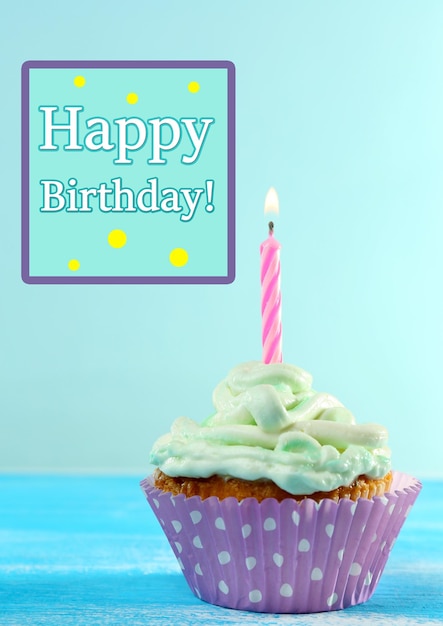 Delicious birthday cupcake on table on light blue background