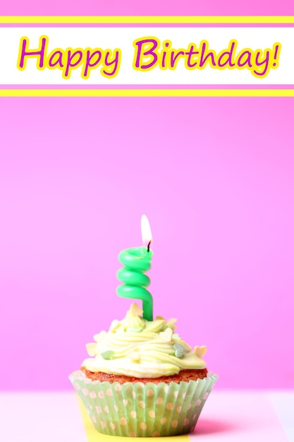 Delicious birthday cupcake on table on pink background
