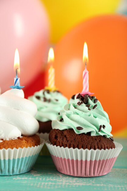 Delicious birthday cupcakes on table on bright background