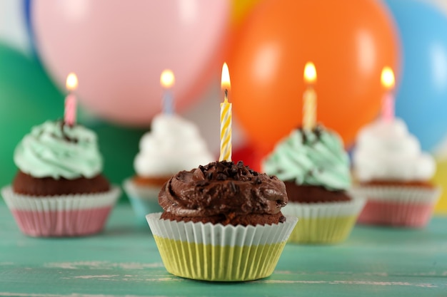 Delicious birthday cupcakes on table on bright background