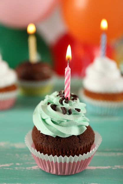 Delicious birthday cupcakes on table on bright background