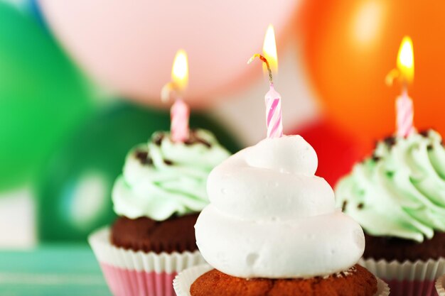 Delicious birthday cupcakes on table on bright background