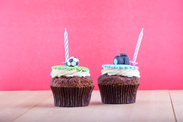 Delicious birthday cupcakes with icons of ball and camera on it