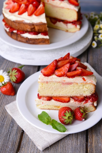 Delicious biscuit cake with strawberries on table closeup