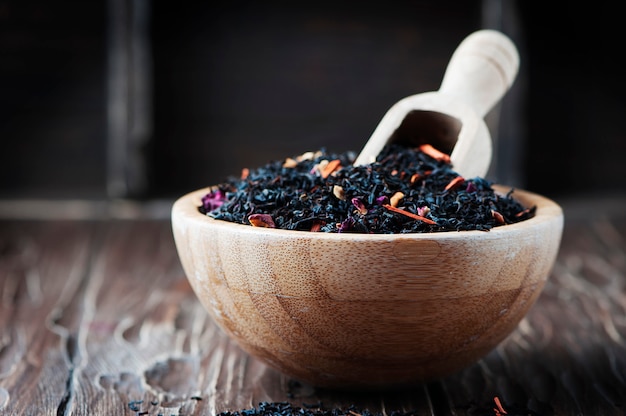 Delicious black tea with petals on the wooden table