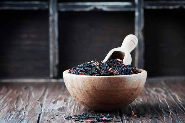 Tè nero delizioso con i petali sulla tavola di legno