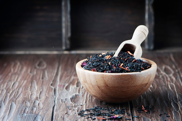 Delicious black tea with petals on the wooden table