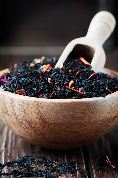 Delicious black tea with petals on the wooden table