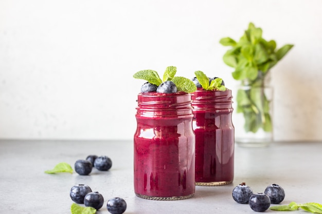 Delicious blueberry smoothie with fresh berries and mint in glass jars. Summer healthy drink.