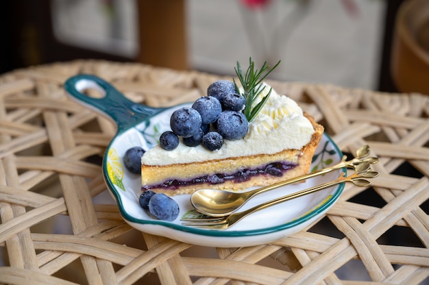 Delicious Blueberry tart with vanilla cream and blueberry filling on white dish