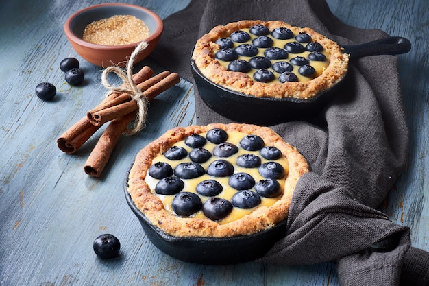 Delicious Blueberry tartlets with vanilla custard cream on light rustic table.