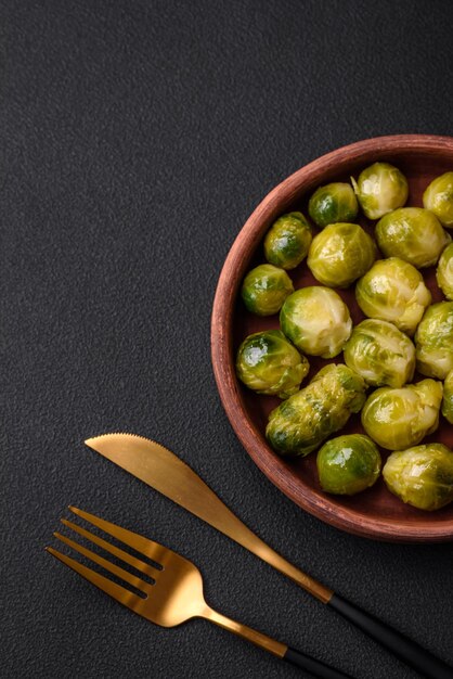 Delicious boiled Brussels sprouts on a ceramic plate on a dark concrete background