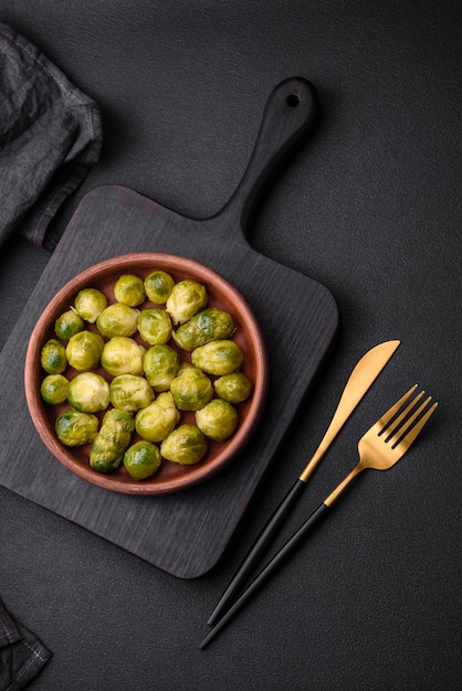 Delicious boiled Brussels sprouts on a ceramic plate on a dark concrete background