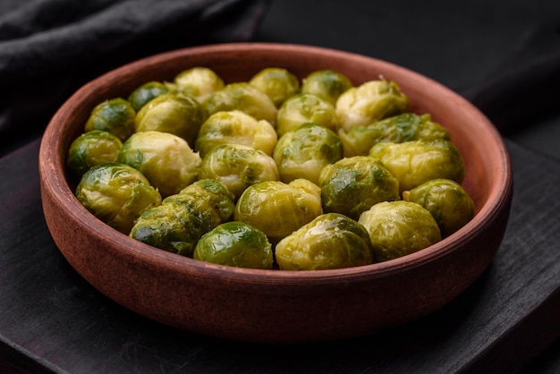 Delicious boiled Brussels sprouts on a ceramic plate on a dark concrete background