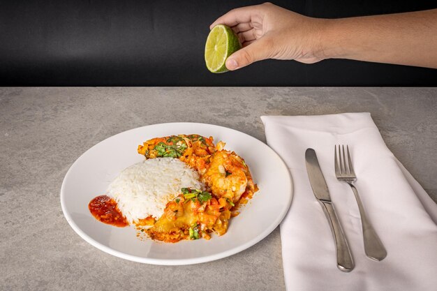 Delicious Brazilian fish moqueca with tomato onion olive oil coriander and orocum seed Served on a white porcelain plate with rice