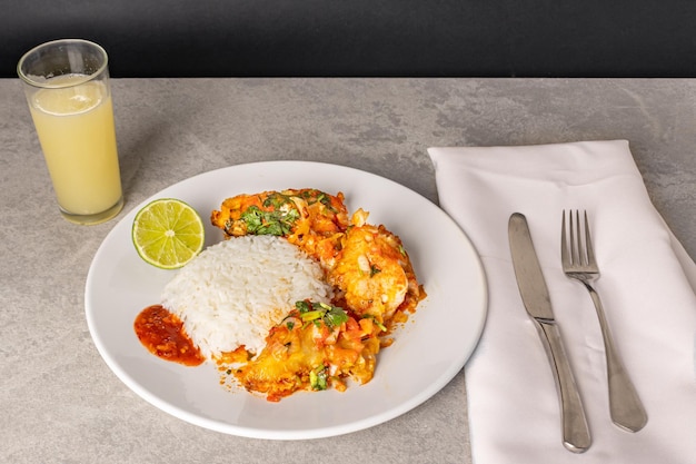 Delicious Brazilian fish moqueca with tomato onion olive oil coriander and orocum seed Served on a white porcelain plate with rice